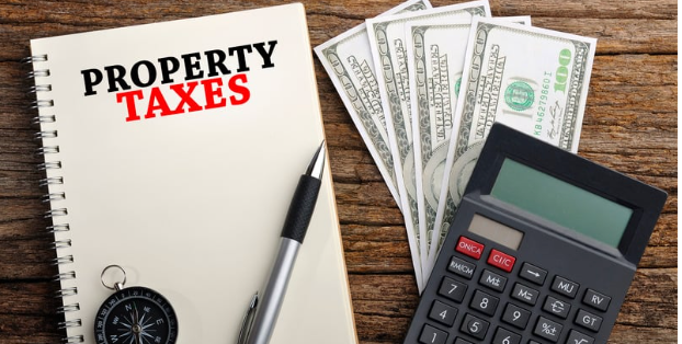 Calculator with $100 bills and a spiral notebook showing the word property taxes